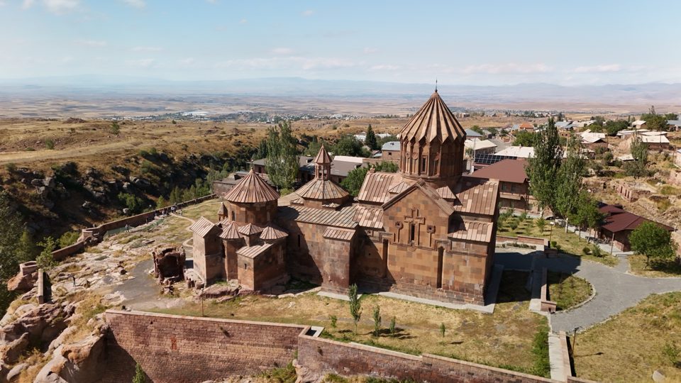 Aerial view of Harichavank Monastery beside a gorge, with the village and plain behind
